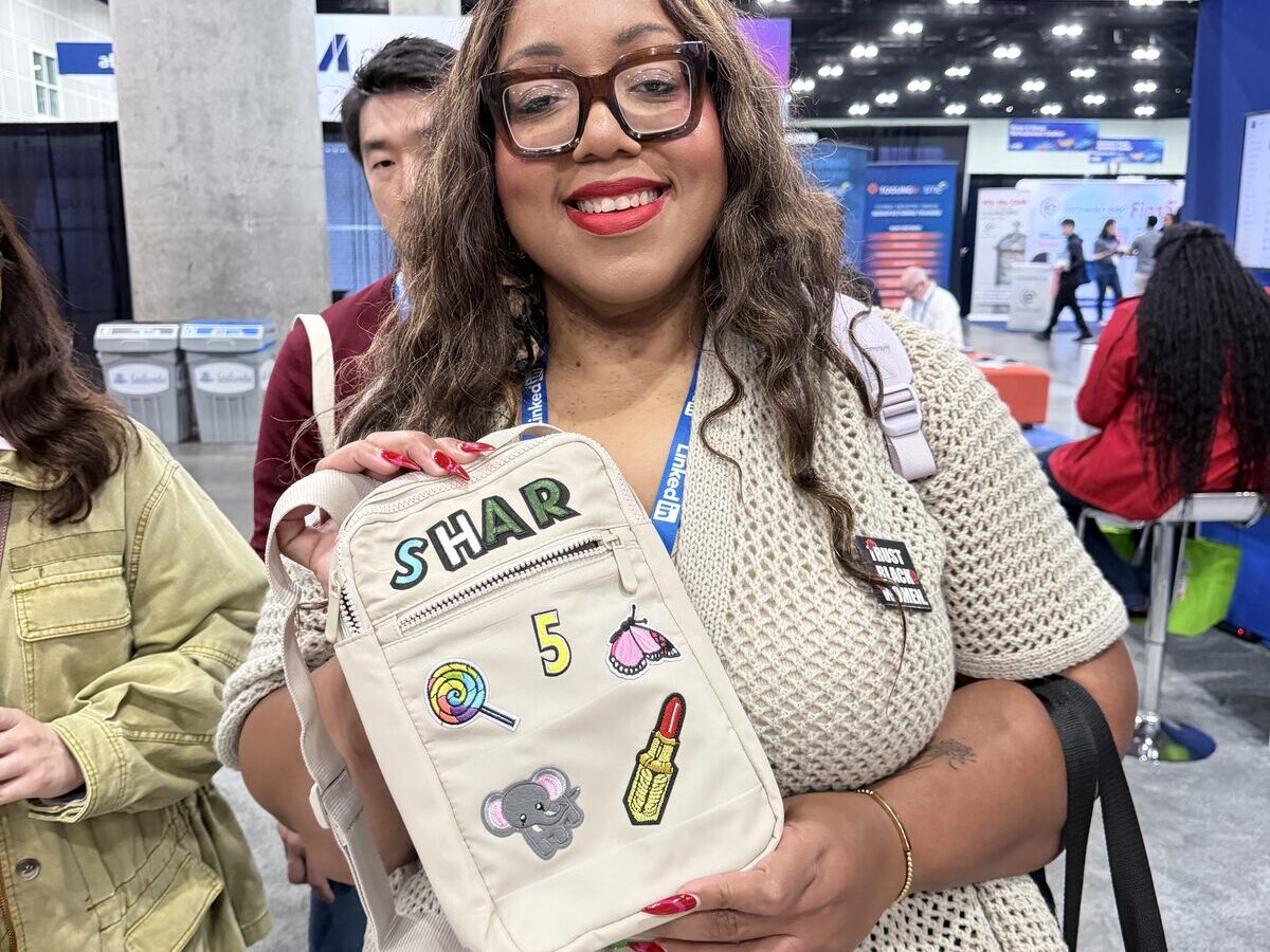 Smiling guest holding a cream bag customized with name letters and colorful pressed patches